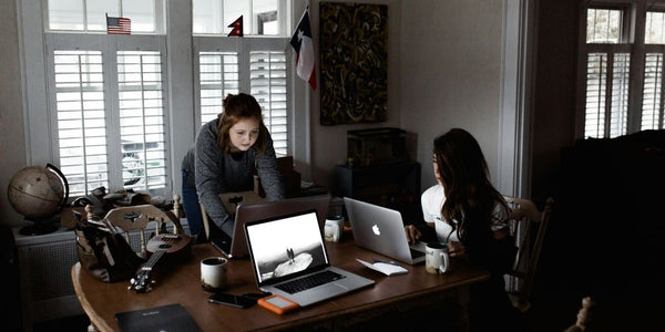 women using laptop on brown wooden table