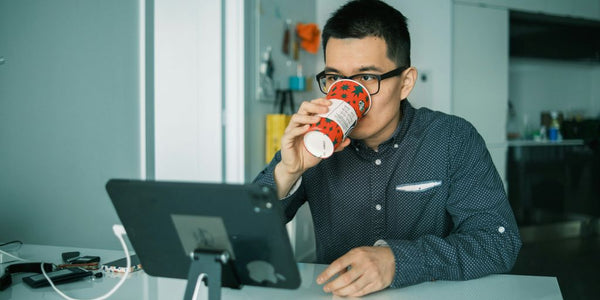 man in black and white checkered dress shirt drinking from brown and white ceramic mug